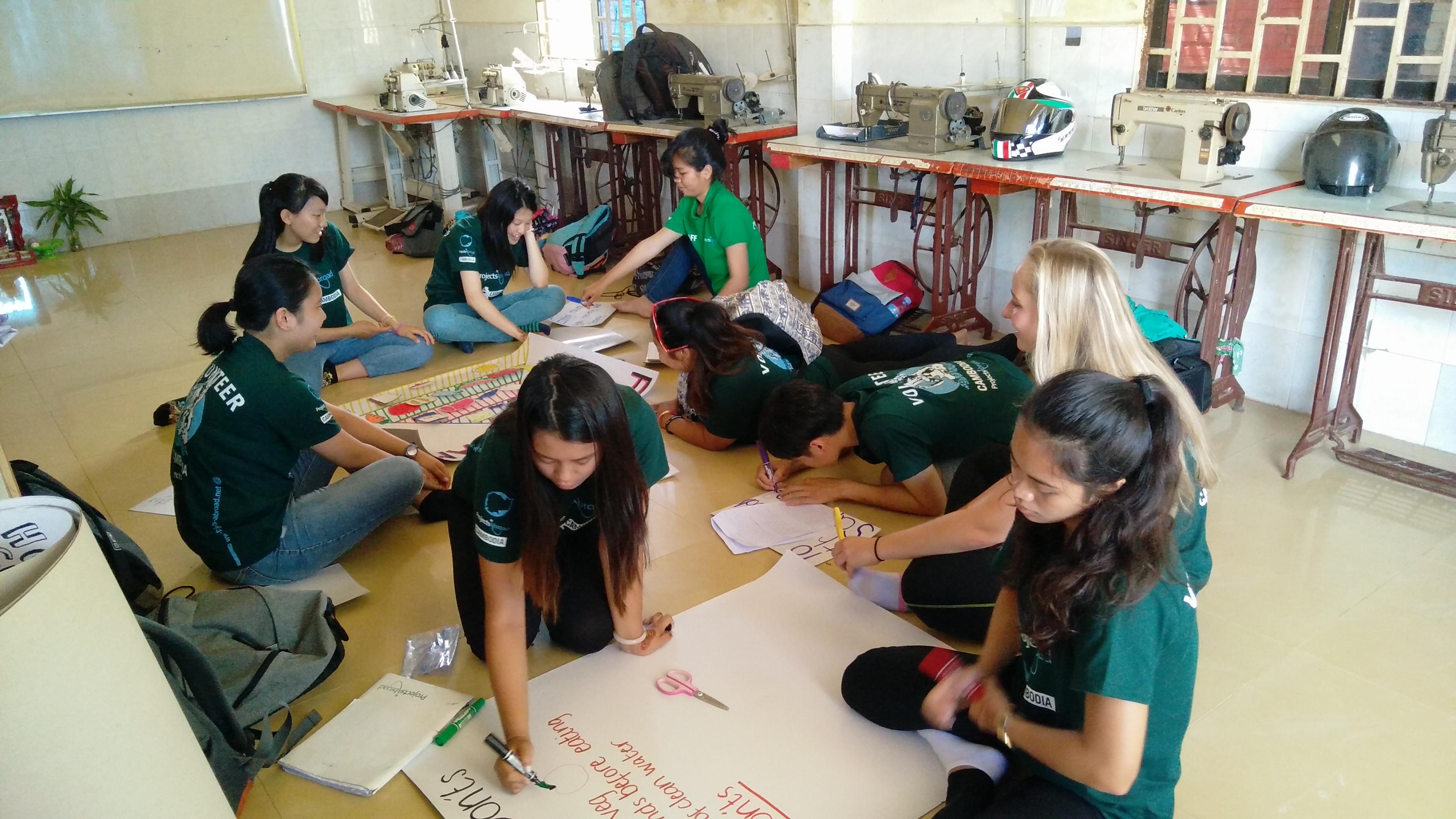 Projects Abroad interns making posters to give nutrition advice during their public health internship in Cambodia. Interns from Projects Abroad can be seen in a classroom making posters to promote nutrition information during their public health internship in Cambodia.